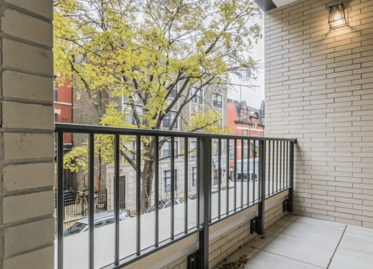a balcony with a black railing and a city street in the background