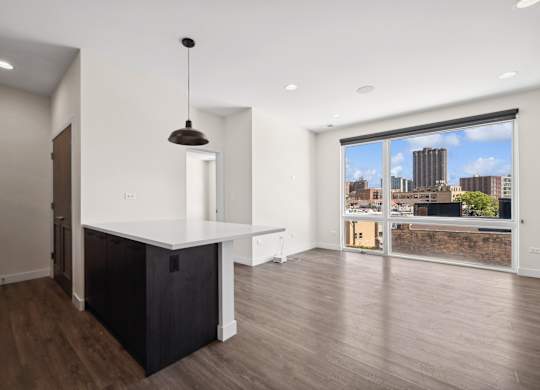 Open kitchen and living room at Highpoint Buena Park on Broadway featuring modern finishes, stainless steel appliances, and floor-to-ceiling windows with city views in a Chicago apartment