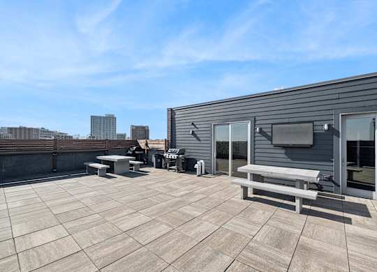 A rooftop patio with a table and chairs and a television.