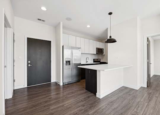 A modern kitchen with a black door and a white countertop.