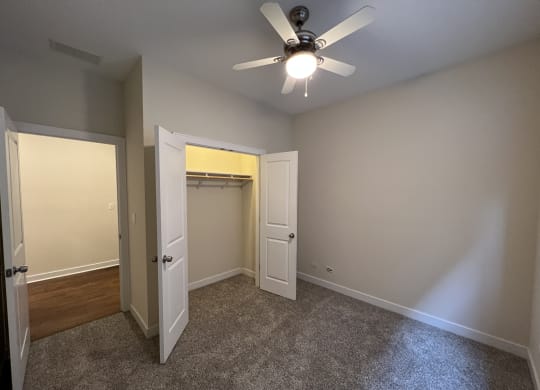 an empty bedroom with a ceiling fan and a closet