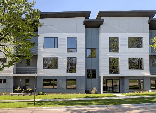 a white and gray apartment building with trees in front of it
