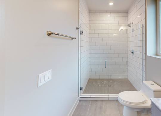 A white toilet is in a bathroom with a walk-in shower.