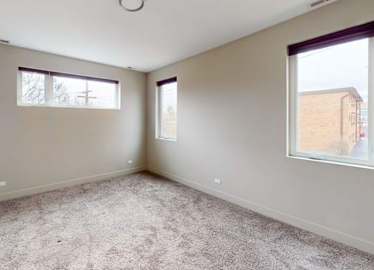 Empty room with carpeted floor and two windows.