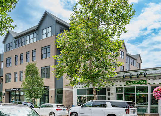 A building with cars parked in front and a sign that says Pizza by Sal.