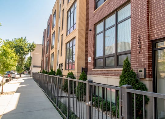a sidewalk in front of a brick building with a fence at Montrose 3634, Chicago Illinois