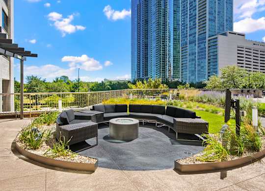 A modern outdoor seating area with a circular table surrounded by chairs and plants.
