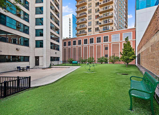 A green bench sits in a grassy courtyard.