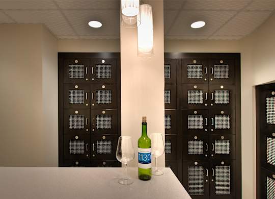 A bottle of wine with a green label is on a table in front of a cabinet.