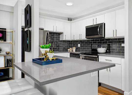 A modern kitchen with a grey countertop and white cabinets.