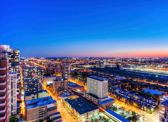 A cityscape at night with buildings illuminated and streets bustling with activity.