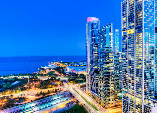 A cityscape at night with a large body of water in the background.