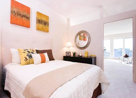A bedroom with a large bed and two paintings on the wall.