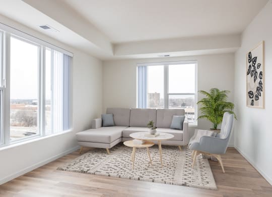 a living room with a gray couch and a rug and large windows