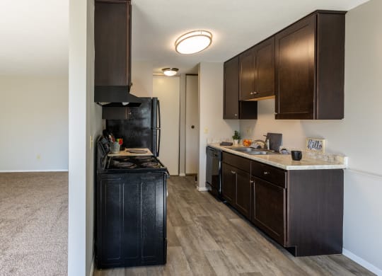 a kitchen with dark wood cabinets and a black stove and refrigerator