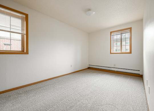 the living room of an empty house with white walls and two windows at Ames Lake Neighborhood Apartments, St. Paul, MN