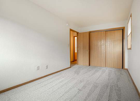 a spacious living room with carpet and a door to a bedroom at Ames Lake Neighborhood Apartments, St. Paul, Minnesota
