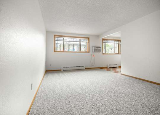 the living room and dining room of a house with white walls and a carpet at Ames Lake Neighborhood Apartments, St. Paul
