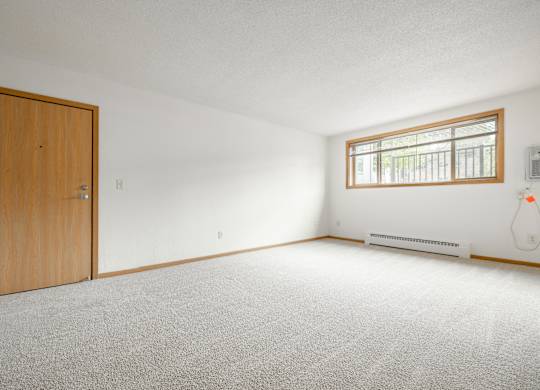 the living room of an empty house with a wooden door at Ames Lake Neighborhood Apartments, Minnesota, 55106