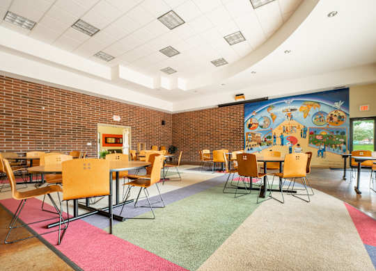 a dining room with tables and chairs and a mural on the wall at Ames Lake Neighborhood Apartments, St. Paul, MN