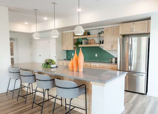 A modern kitchen with a long island and grey barstools.