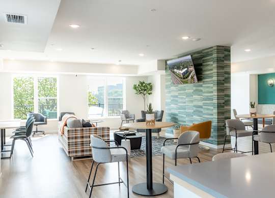 A modern living room with a large window, a couch, a coffee table, and a TV mounted on the wall.