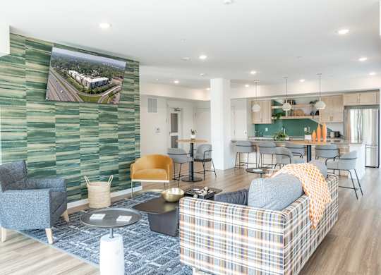 A living room with a plaid couch and a green wallpapered wall.