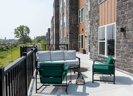 A patio with a green chair and a white couch.