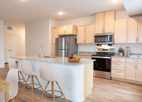 a kitchen with a large island with white chairs and a counter top