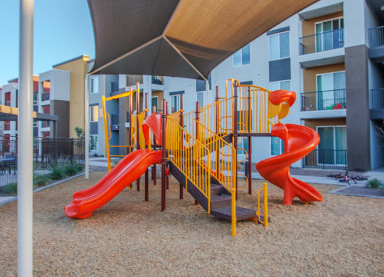 a playground at an apartment complex with a yellow and red spiral slide