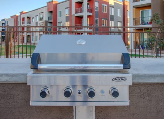 a stainless steel grill with an apartment building in the background