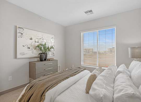 A bedroom with a large bed and a painting on the wall at Copa Flats Apartments, Maricopa
