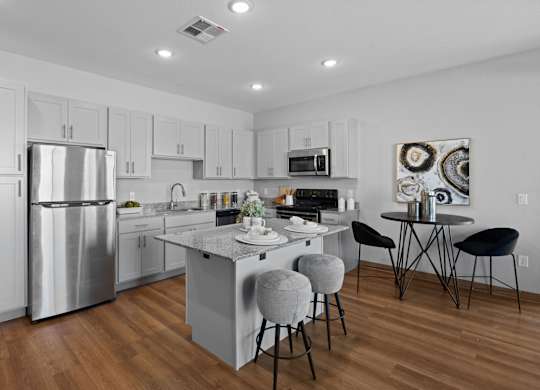 A modern kitchen with a large island and stools at Copa Flats Apartments, Maricopa, Arizona