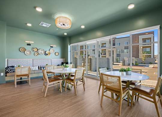 A dining room with a table set for four and a view of a building outside the window at Copa Flats Apartments, Maricopa, Arizona