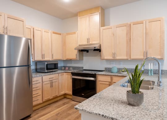 a kitchen with wooden cabinets and granite counter tops and a stainless steel refrigerator
