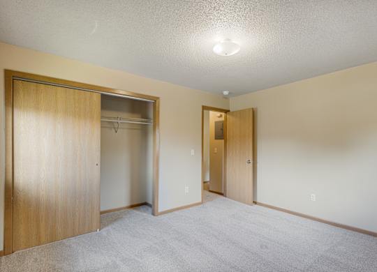A room with a carpeted floor and two open doors.