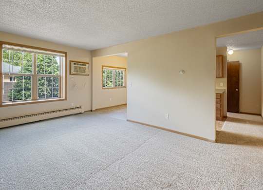 A spacious room with a carpeted floor and a door on the right side.