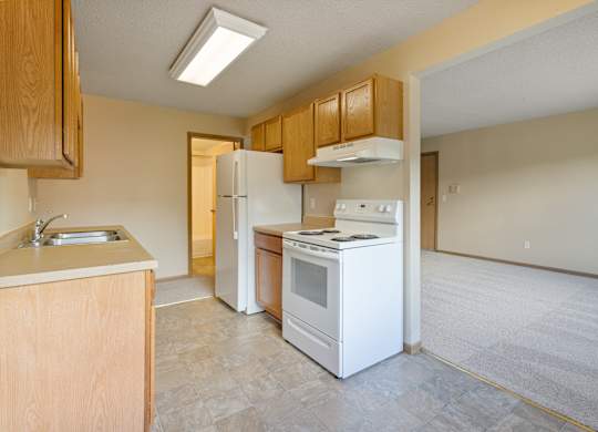 A kitchen with white appliances and wooden cabinets.