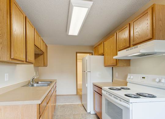 A kitchen with wooden cabinets and a white stove top oven.