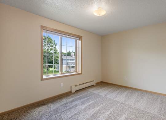 A room with a window and a carpeted floor.