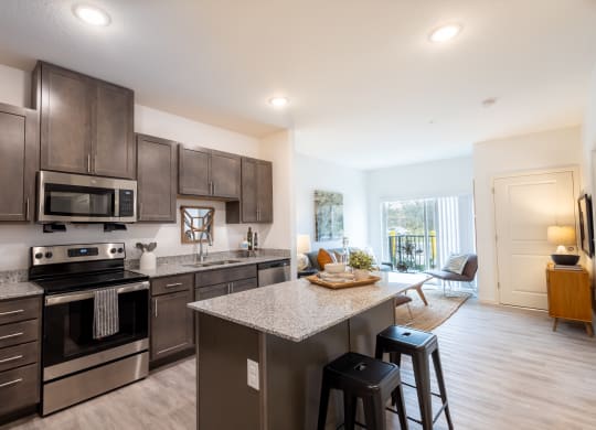 an open kitchen with stainless steel appliances and a granite counter top