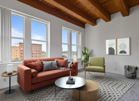 a living room with a couch and a coffee table and three windows