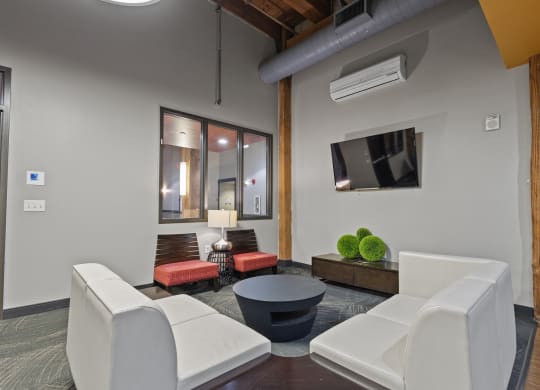 a living room with white furniture and a tv on the wall