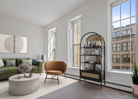 a living room with a green couch and a round coffee table and two windows