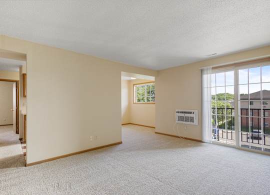 A spacious room with a white carpet and a large window.