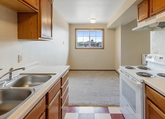 A kitchen with a stove, sink, and window.