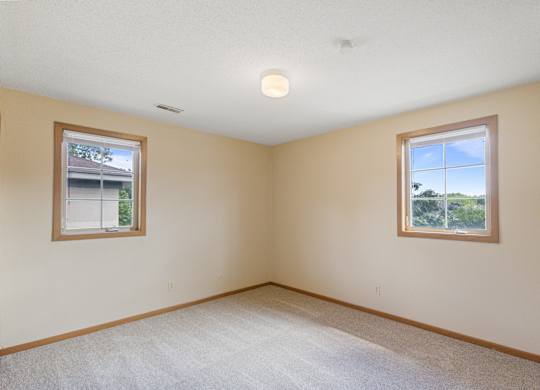 A room with two windows and carpeted flooring.
