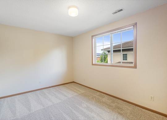 A room with a window and a carpeted floor.