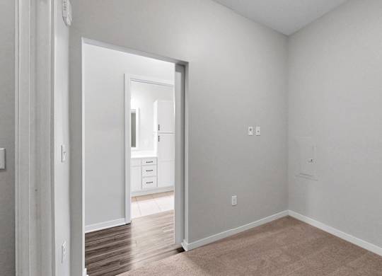 A room with white walls and a doorway leading to another room.