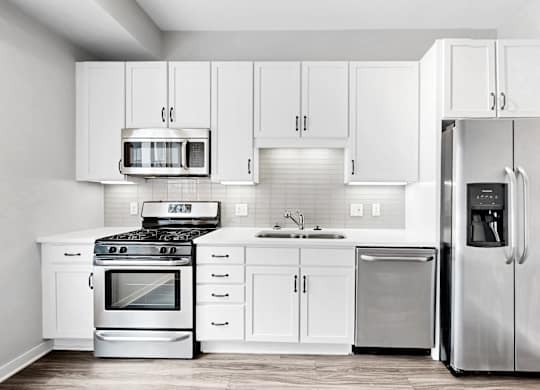 A modern kitchen with white cabinets and stainless steel appliances.